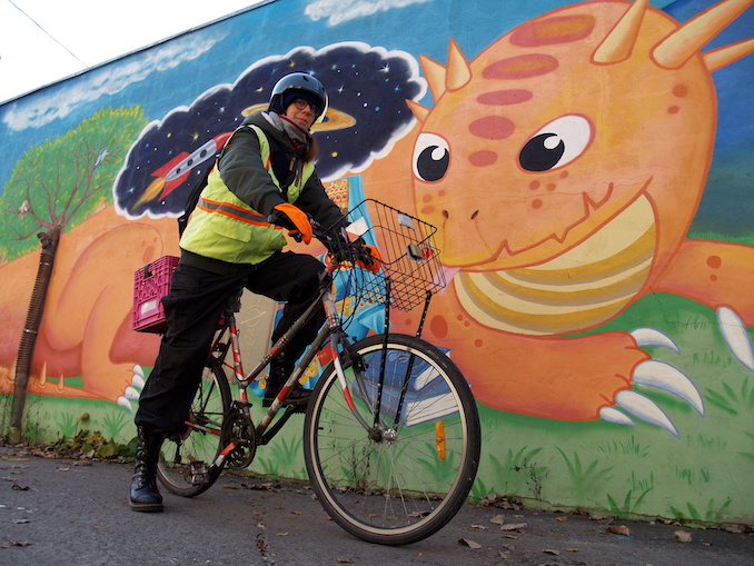 Je voyage à vélo la plupart du temps, même en hiver. J’aime l’indépendance et la liberté que cela me donne. Me voici qui pose devant une murale que nous avons fait dans notre ruelle, mon conjoint Luc et moi, le sujet de la murale ayant été déterminé par les enfants de la ruelle.