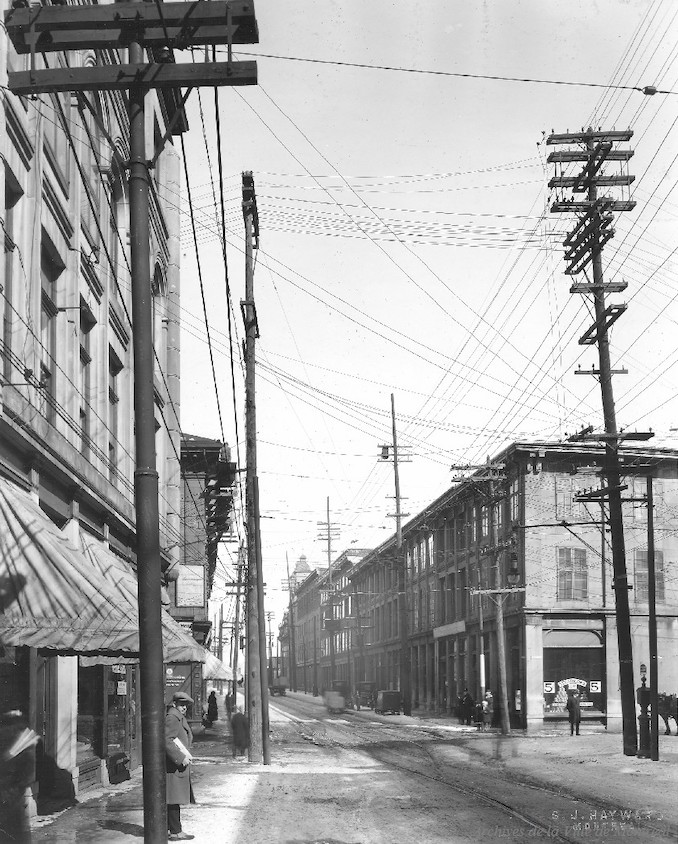 1925-Photographie de la rue Notre-Dame en direction est vers la rue Bonsecours dans le Vieux-Montréal, avant l'enfouissement des fils électriques.