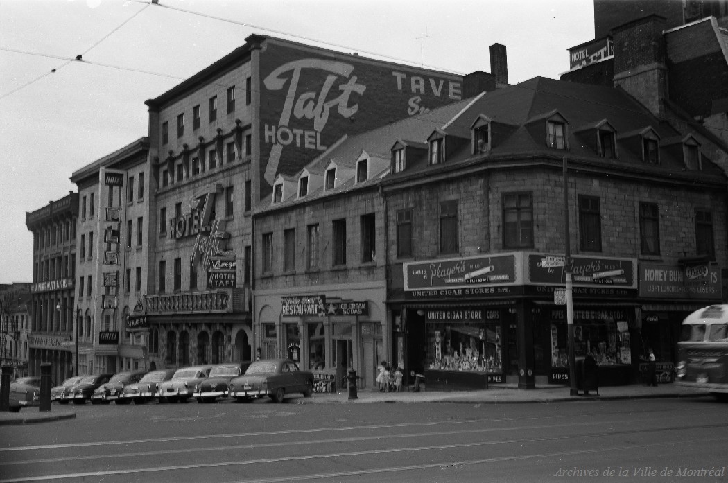 1953-Photographie de l'intersection sud-ouest de la rue Notre-Dame et de la place Jacques-Cartier. On y voit l'Hôtel Plaza, l'Hôtel Taft, le Golden Star Restaurant, un magasin United Cigar Stores