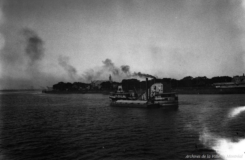 1926-Photographie d'un bateau naviguant sur le fleuve Saint-Laurent en face des rives de Saint-François-d'Assise-de-la-Longue-Pointe. On y aperçoit l'église de la paroisse