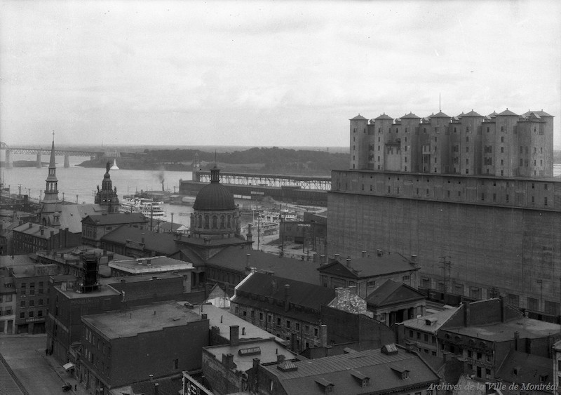 1933-Photographie aérienne oblique du Vieux-Montréal. On y voit le marché Bonsecours, le port ainsi que l'élévateur de grains no. 2.