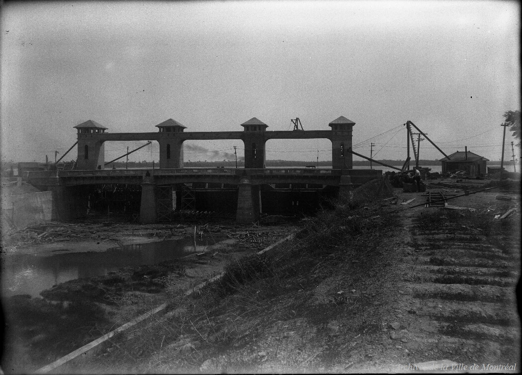 1920 - Vue en aval de la construction du pont Lasalle, à l'entrée du canal de l'Aqueduc. Vue vers l'ouest du pont, depuis la rive nord Canal de l'Aqueduc.