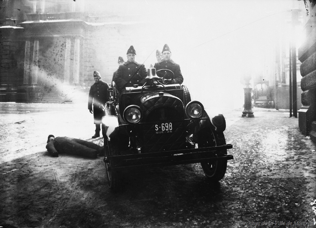 1926 - Photographie de pompiers à bord d'une autopompe sur la rue Saint-Pierre en direction nord, au coin de la rue Saint-Jacques Ouest lors d'une simulation d'accident.