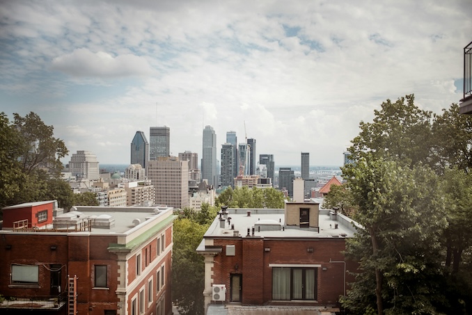 Montreal skyline with buildings and trees in front of the view. 