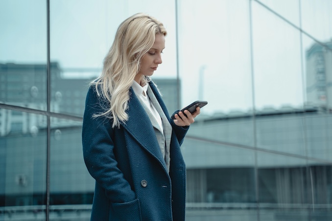 Woman wearing a blue jacket using a cell phone outside